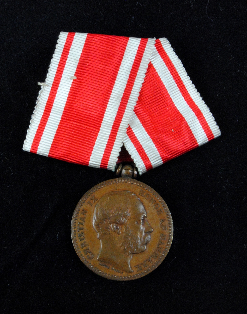 "Erindringsmedalje for Krigen 1864". Medaljen pryds av Christian IX:s profil i relief. Medaljen har ett röd- och vitrandigt ordensband.