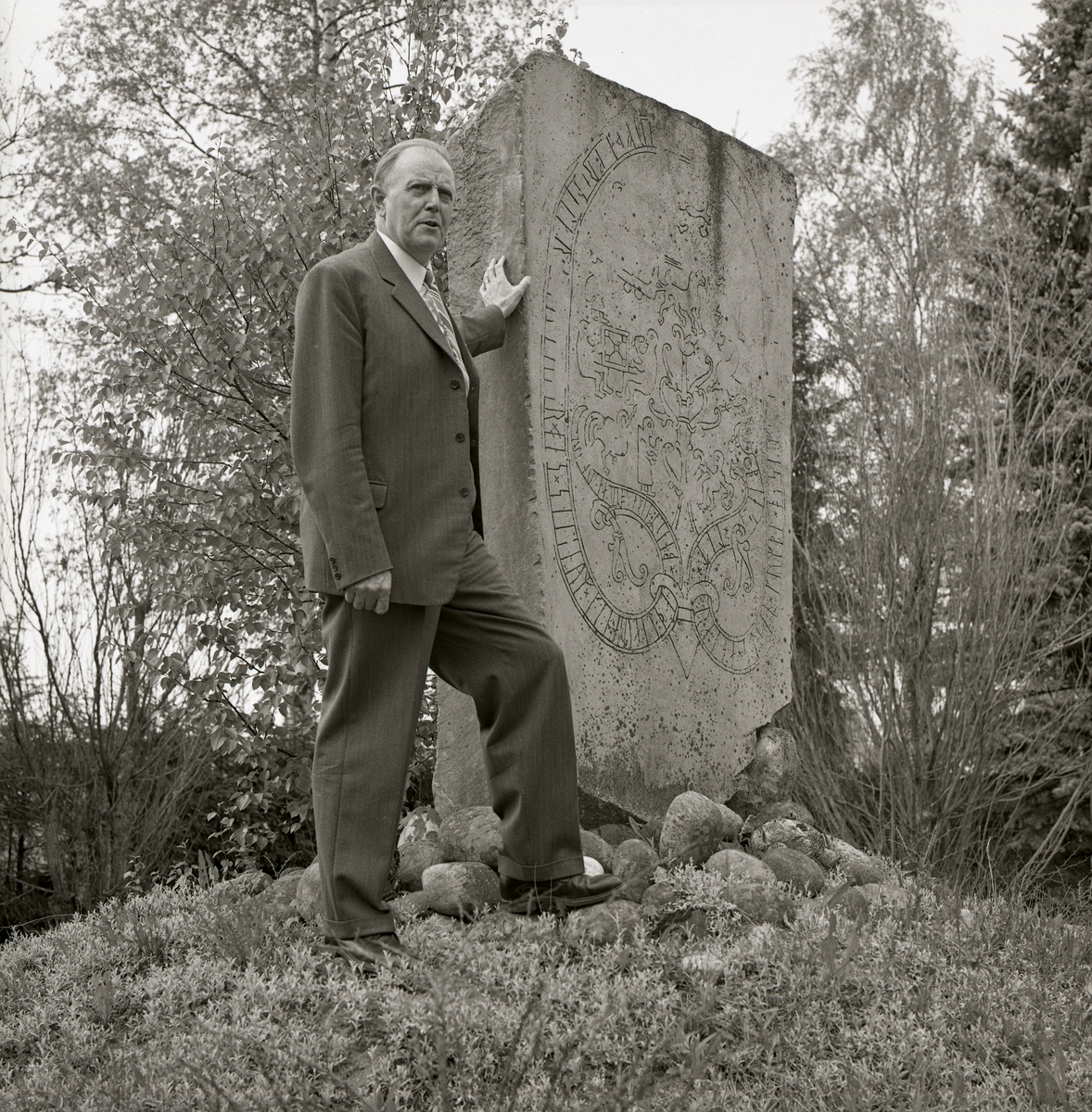 En man står bredvid en runsten på en kulle vid Gripsholm i Mariefred.