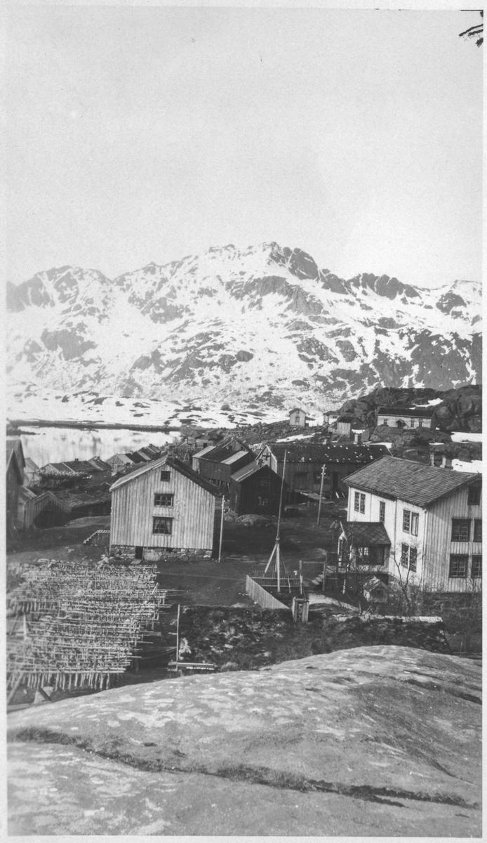 Fiskehjeller og bebyggelse i et fiskevær. Fjell i bakgrunnen. - Sør ...