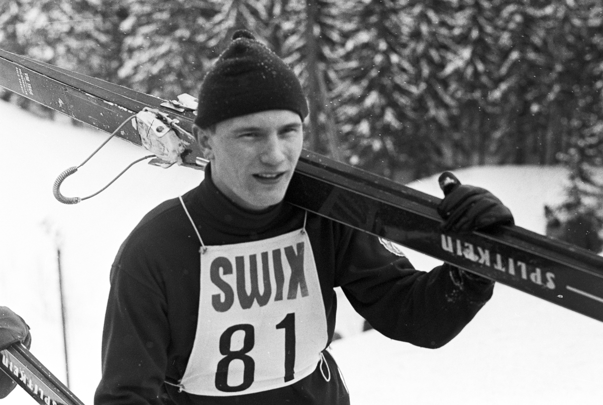 En skihopper bære skiene på skulderen, NM i hopp for junior, Midtstubakken. Fotografert februar 1969.
