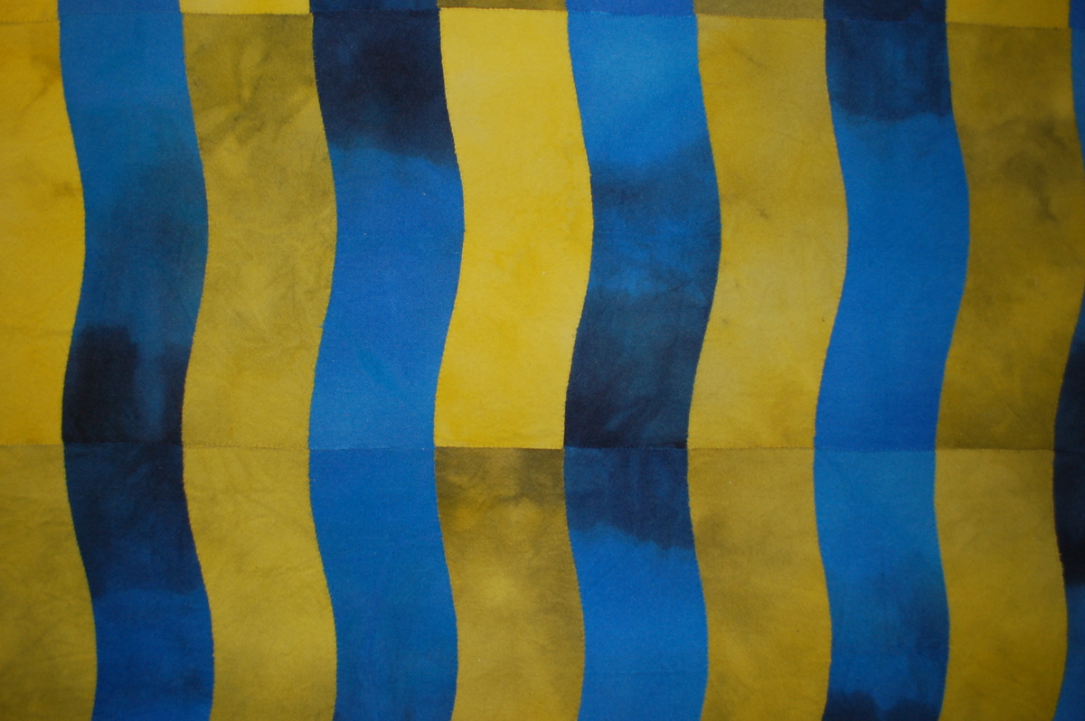 Tekstil med gule og blåe render som bølger seg nedover.