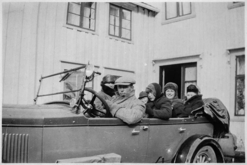Flere personer i en Chrysler Roadster (1928 modell?). W-27 registrert på Gunnar Wikborg Vik som også er sjåføren på bildet. Roadster var betegnelsen på et åpent to-dørs to-seters karosseri. Evt. med 2 plasser i svigermorsete i avrundet bakende, som alternativ til bagasjerom. Dette er en åpen fire-dørs 5-seter (kanskje 7?), som gjerne ble kalt phaeton (=solvogn) på denne tida.