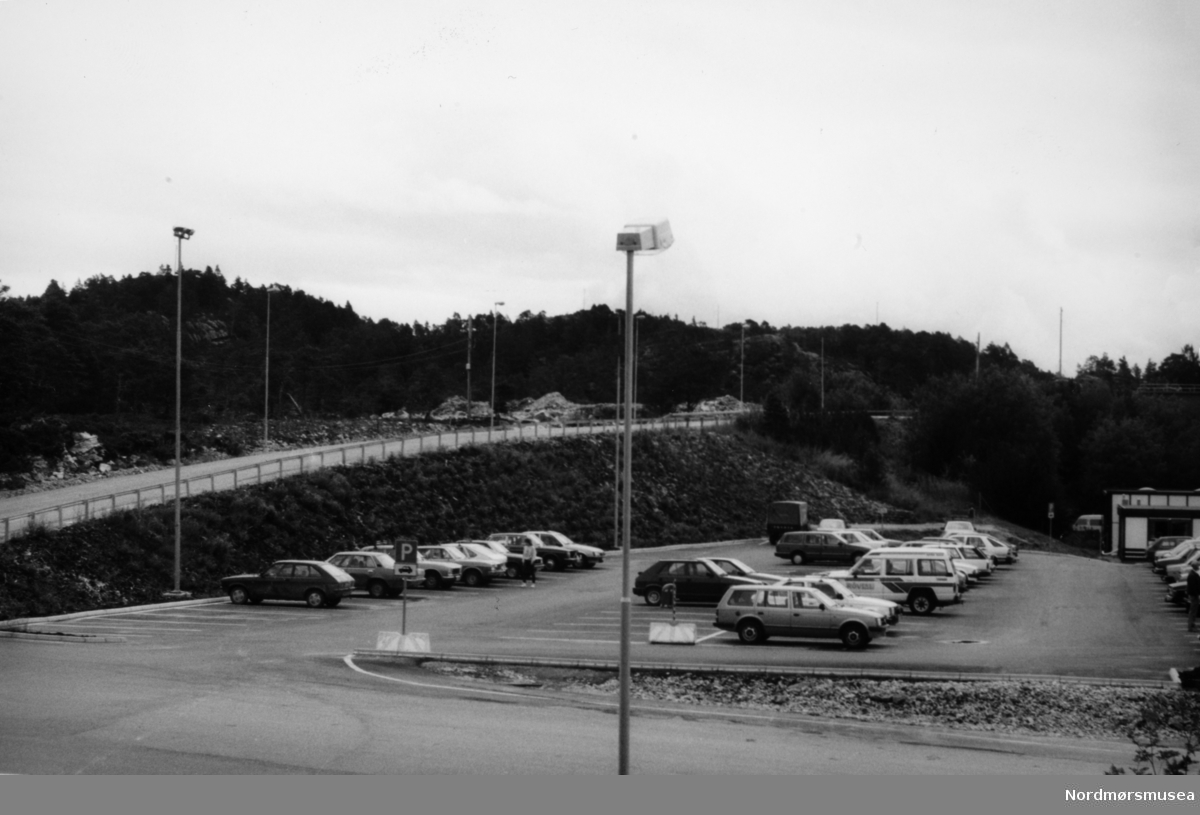 Foto fra parkeringsplassen ved Kvernberget på Løkkemyra i Kristiansund. Datering er muligens omkring 1986-1990. Fotoarkivet stammer fra Nordmørsposten, og inngår nå i Nordmøre museums fotosamlinger.