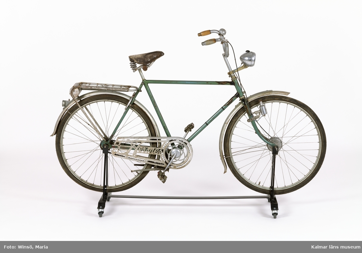 KLM 43197. Cykel, herrcykel av märket Hermes. Ramen är lackerad ljusblå, övriga metalldelar silverfärgade. Med trähandtag, lädersadel, ringklocka, handbroms, lykta med generator, pakethållare med behållare för verktyg och cykelpump. Kedjeskydd med genombrutet stansat mönster samt fabrikatnamnet "Hermes".
Kvitto på när cykeln köptes finns (KLM 43147:16).