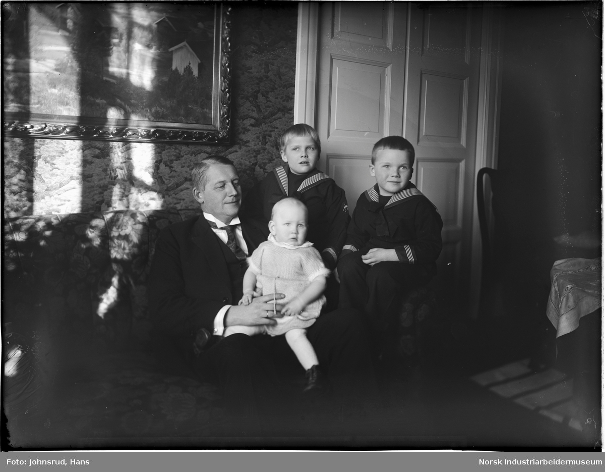 Mann med tre barn fotografert i stue.