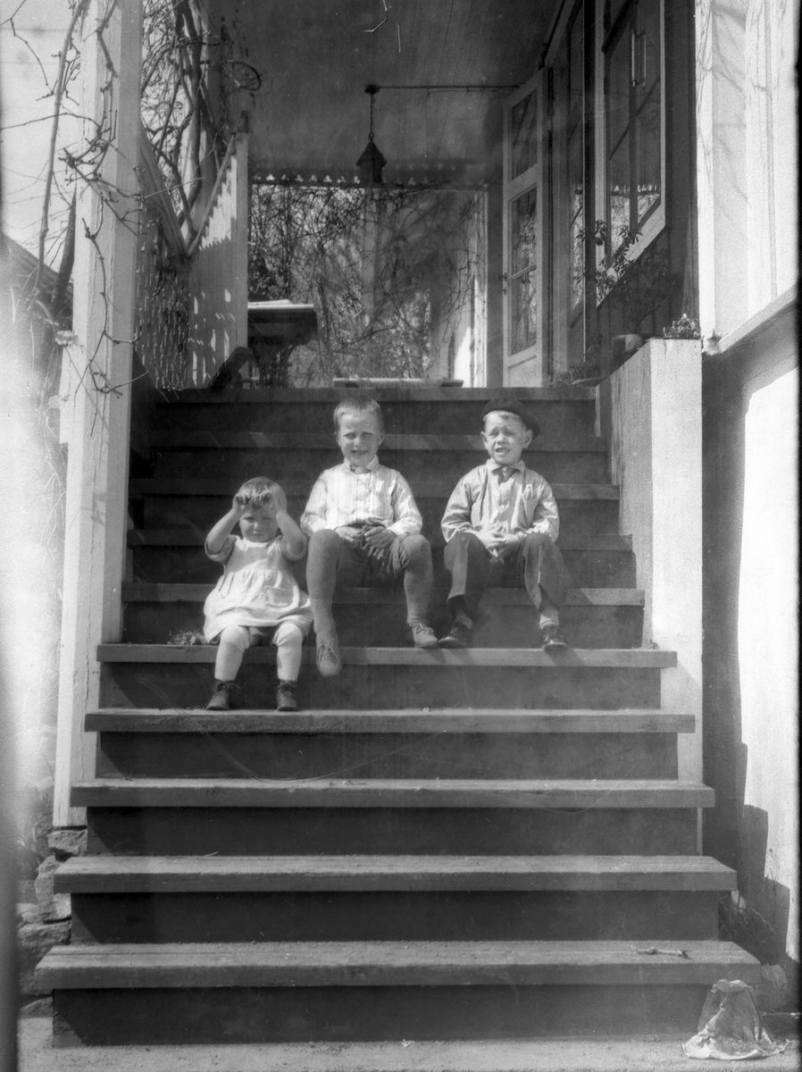 Tre barn sitter på trapp.