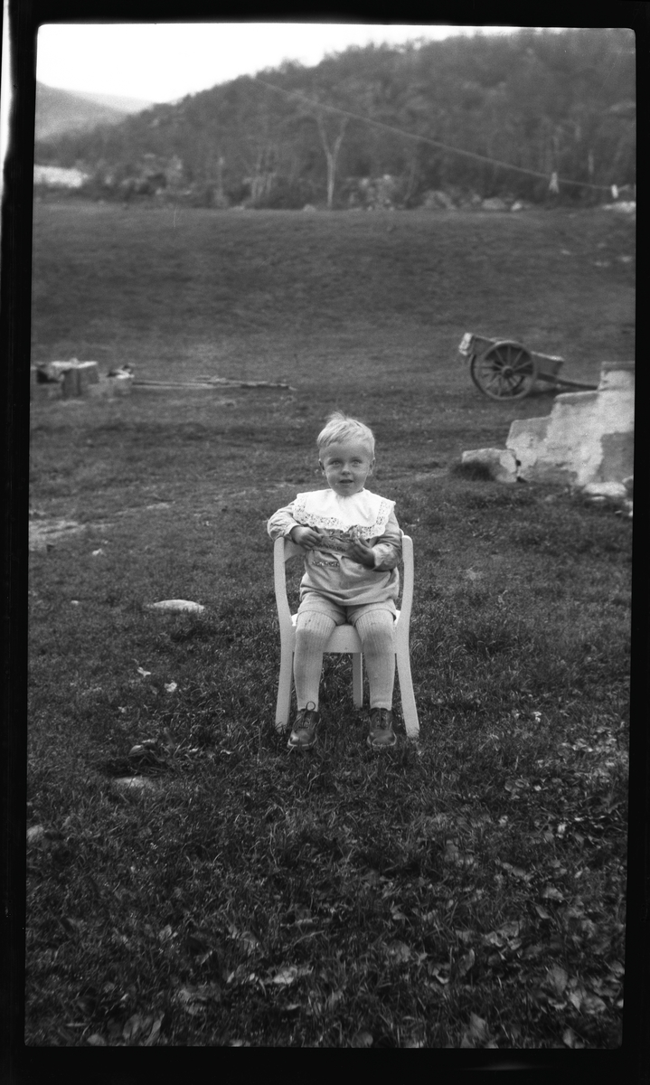 Portrett av liten gutt sittende utendørs.