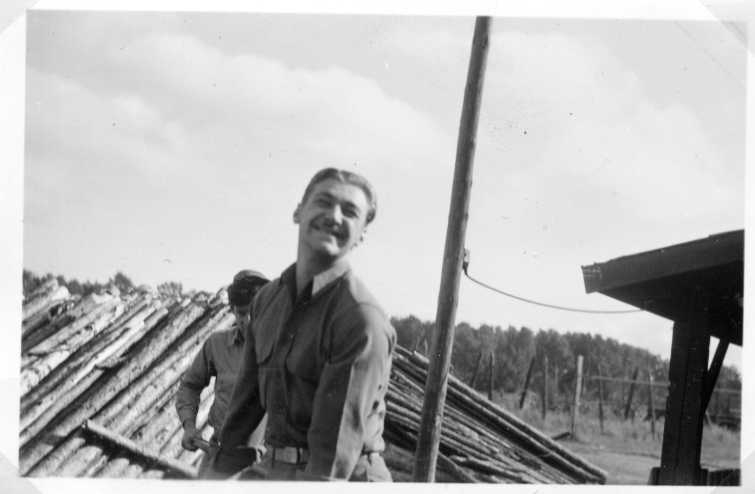 Två män framför en hög med störar, tittar och ler mot fotografen.
Sannolikt samma personer på gm.b4700