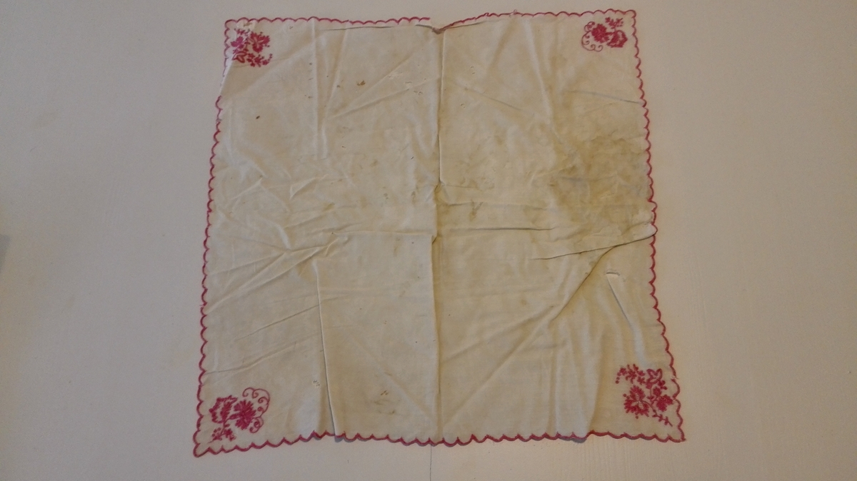 1 bordserviett

Bordserviett av hvit silke. Tunget kanter sydd med rød silke. I hvert hjørne sydd med rød silke et blomsterarrangement. 45,5 x 47,5 cm.