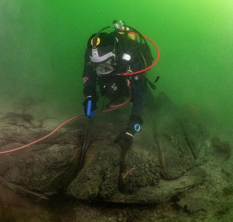 Dykker under vann sager i vrak på sjøbunnen: Arkeolog Elling Utvik Wammer sager ut skiver av hudbord til datering av skipsvraket ved Drengeholmen.