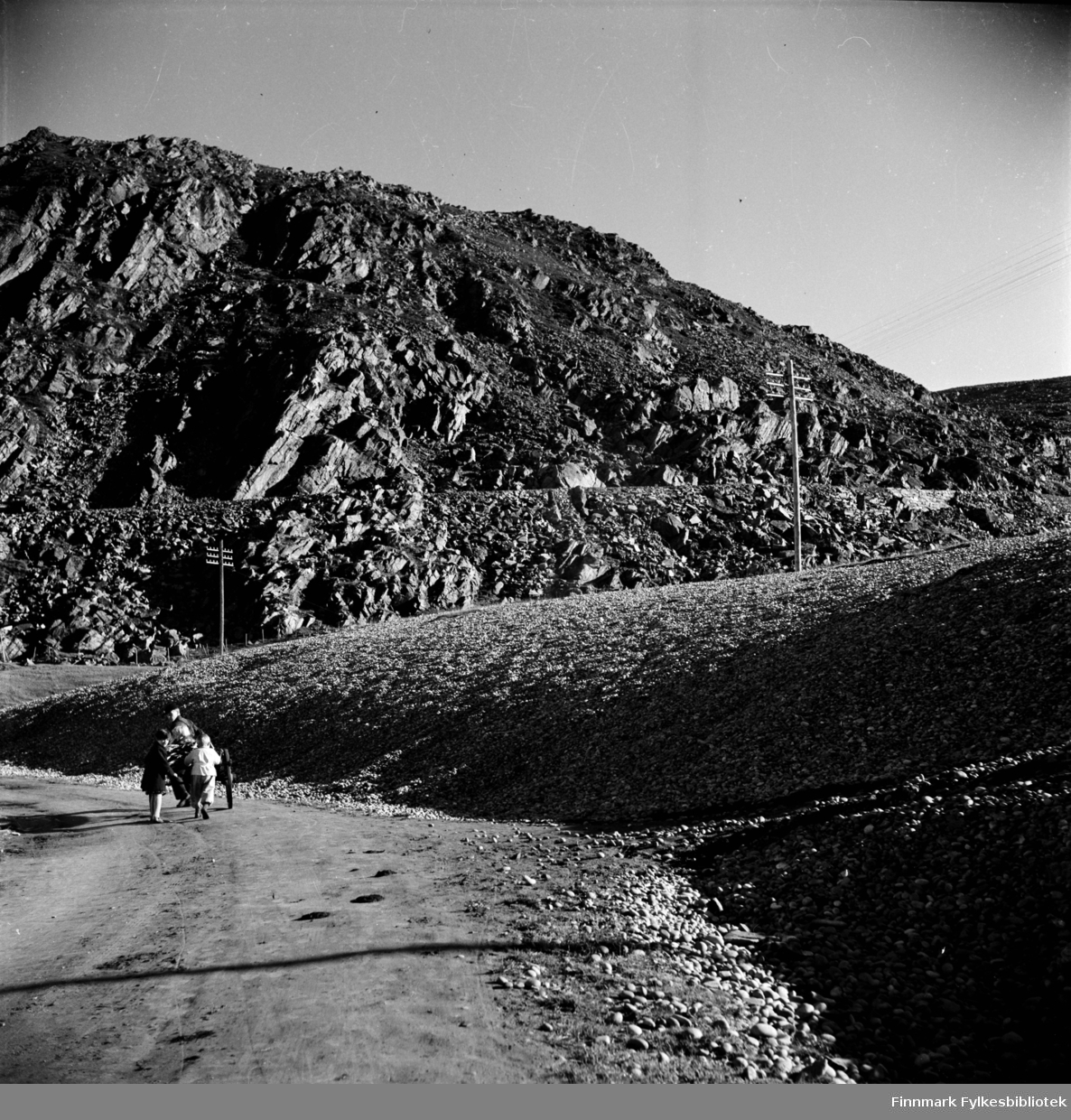 Kjøllefjord 1940,  fotografert av Elisabeth Meyer. To barn følger etter en mann med moped og tralle bakpå. Fotografert omtrent med elva og den gamle veien som fører opp på fjellet i Kjøllefjord. Veien opp fra Kjøllefjord het "Nyveien" og det er sannsynligvis her bildet er tatt.