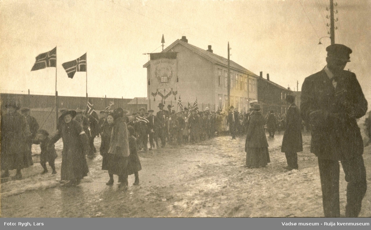 17. maitog i Vadsø med faner og flagg i 1918. Kvinner og barn, en matros til høyre.