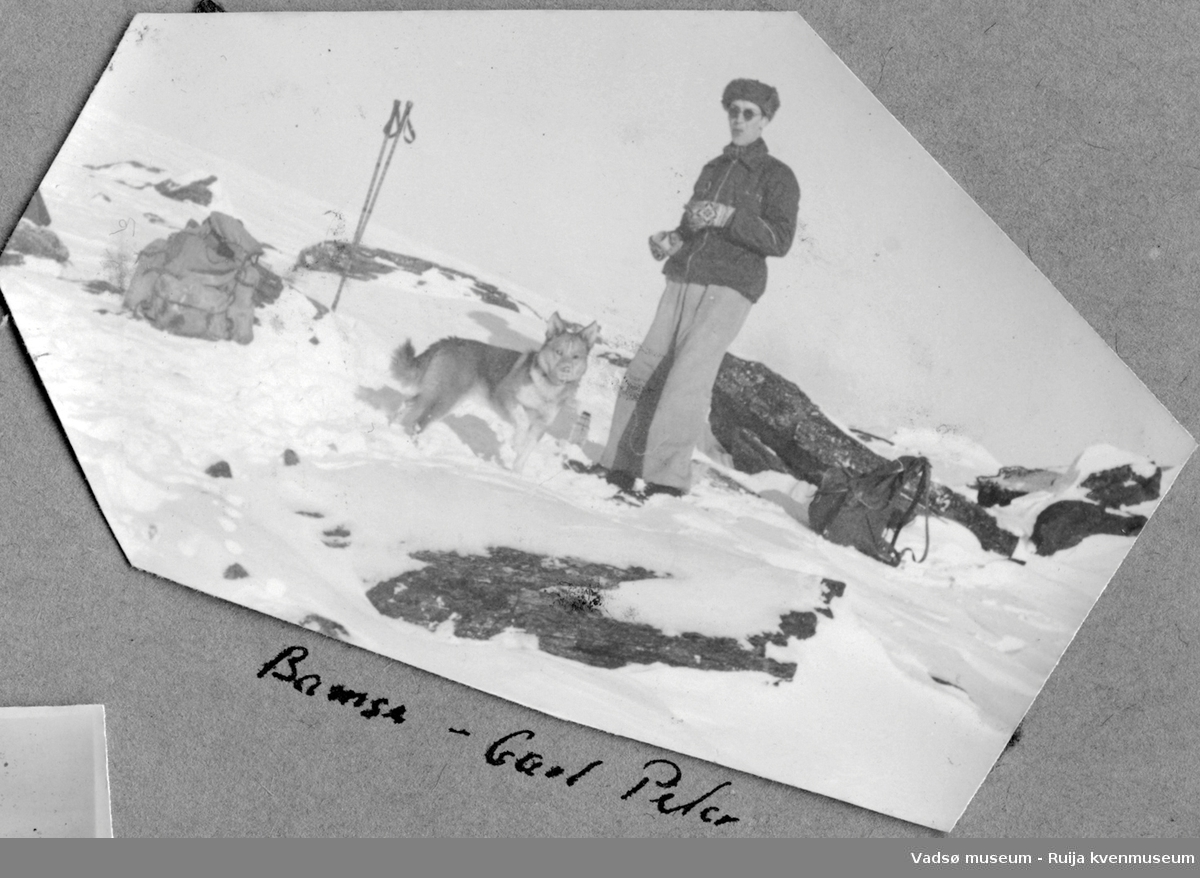 Ung mann og hund avbildet under rast i fjellet vinterstid, et sted utenfor Hammerfest.