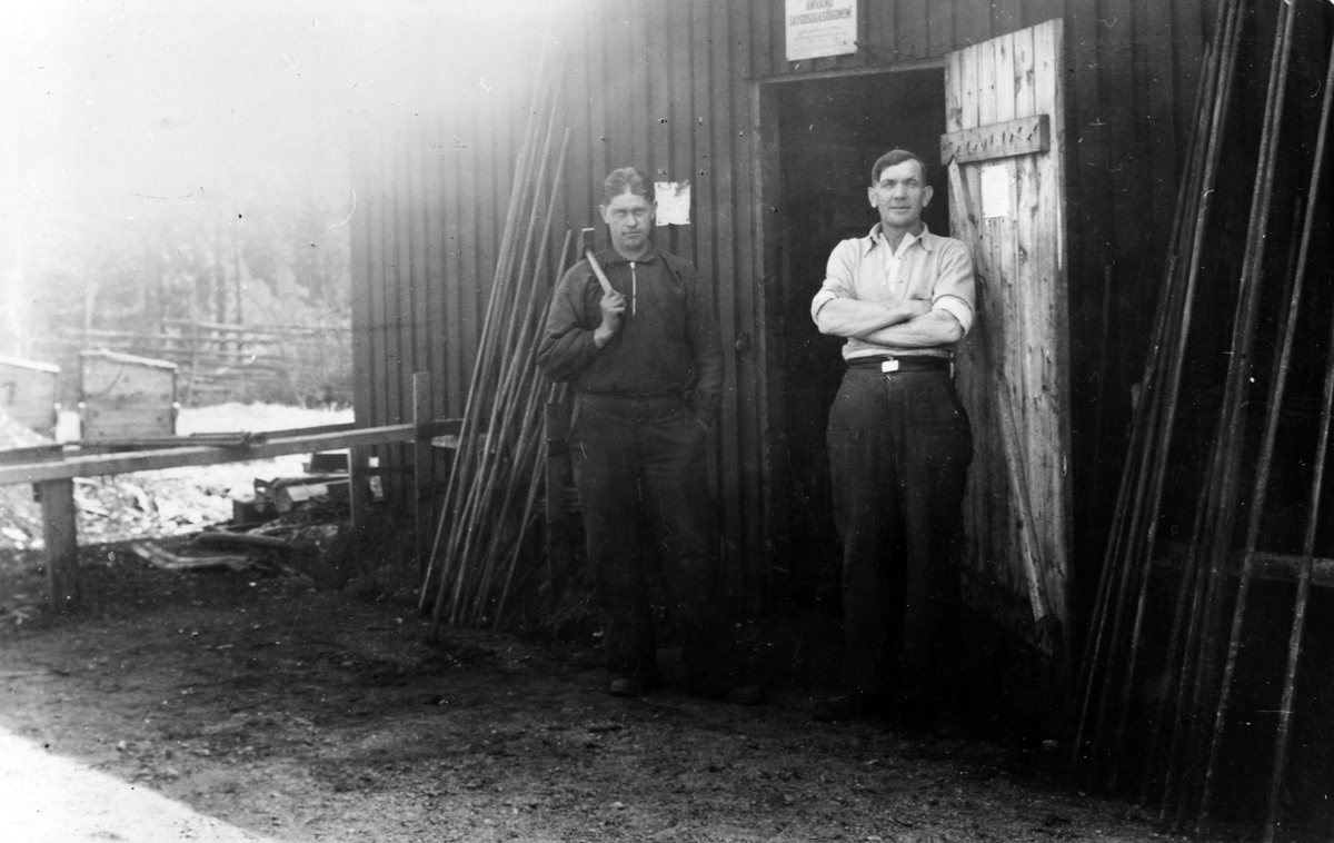 Två stycken arbetare från Statens Arbetlöshetskommision står framför ett träskjul i Fryele, Småland. Till höger står Folke Augustsson, metallarbetare från Alingsås.