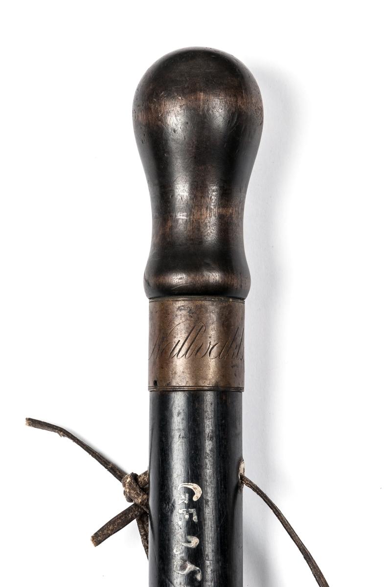 Nattvaktsstav av svartmålat trä, med ring påträdd med texten "Gefle Stads Nattvakt". Käppen är till typen som en spatserkäpp med avlång knopp till handtag. I genomborrat hål är genomdragen en lädergla. Doppsko saknas.