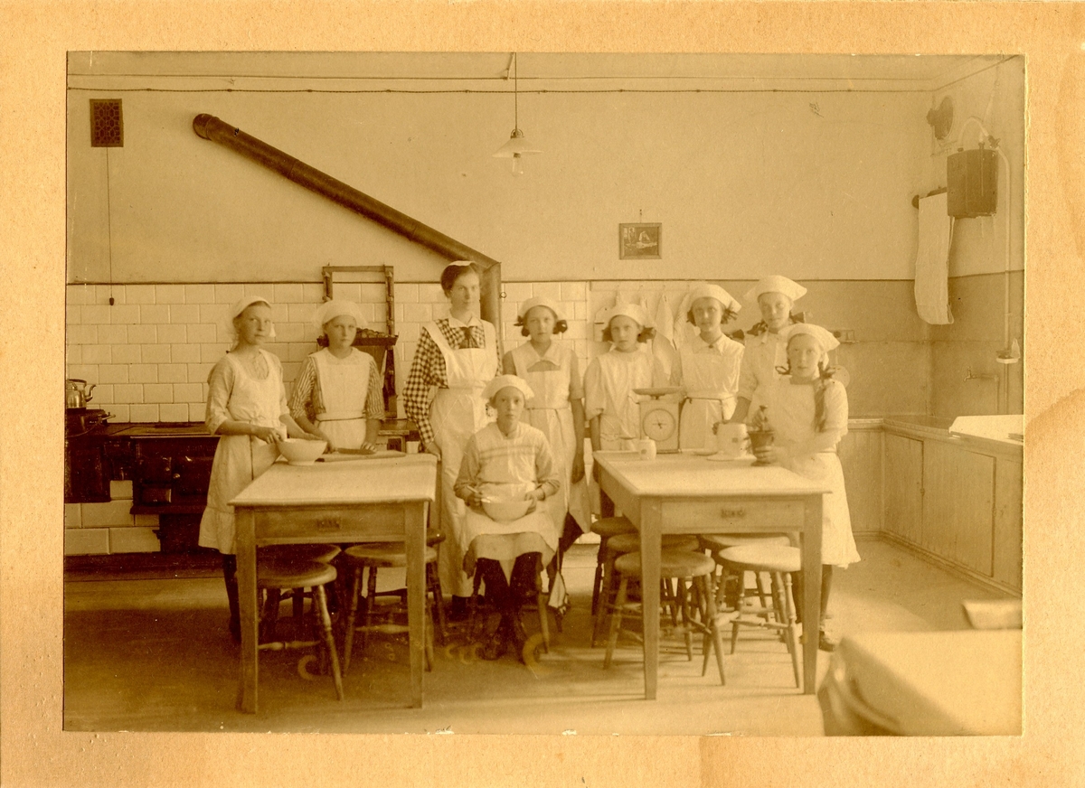 En grupp flickor undervisas i skolköket på Centralskolan. I mitten står lärarinnan Elsa Broman.