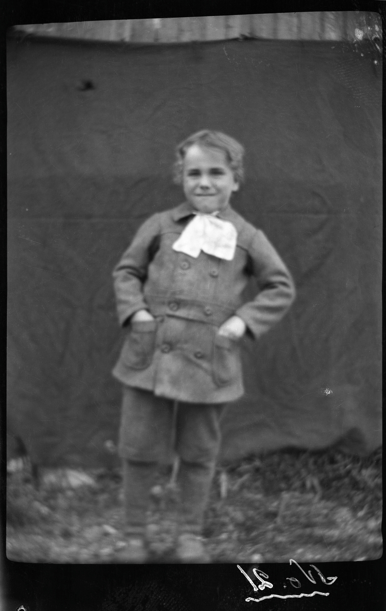 Portrett av gutt stående utendørs.