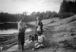 Fire personer ved innsjø i granskog