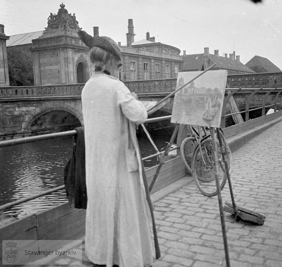 Kvinne maler ved bro og kanal i Venezia.