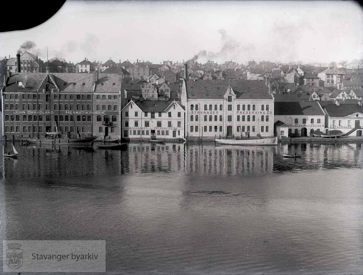 Til venstre John Braadland Hermetikfabrik. Resten av bygningene tilhører Stavanger Preserving Co., også den gamle tollboden helt til høyre. Braadland har nettopp utvidet mot nord (1906)...Fabrikkeier John Braadlands båt, Victoria liggende til venstre i bildet. Bygget i Chatham, 1895, kjøpt av Braadland i 1907.