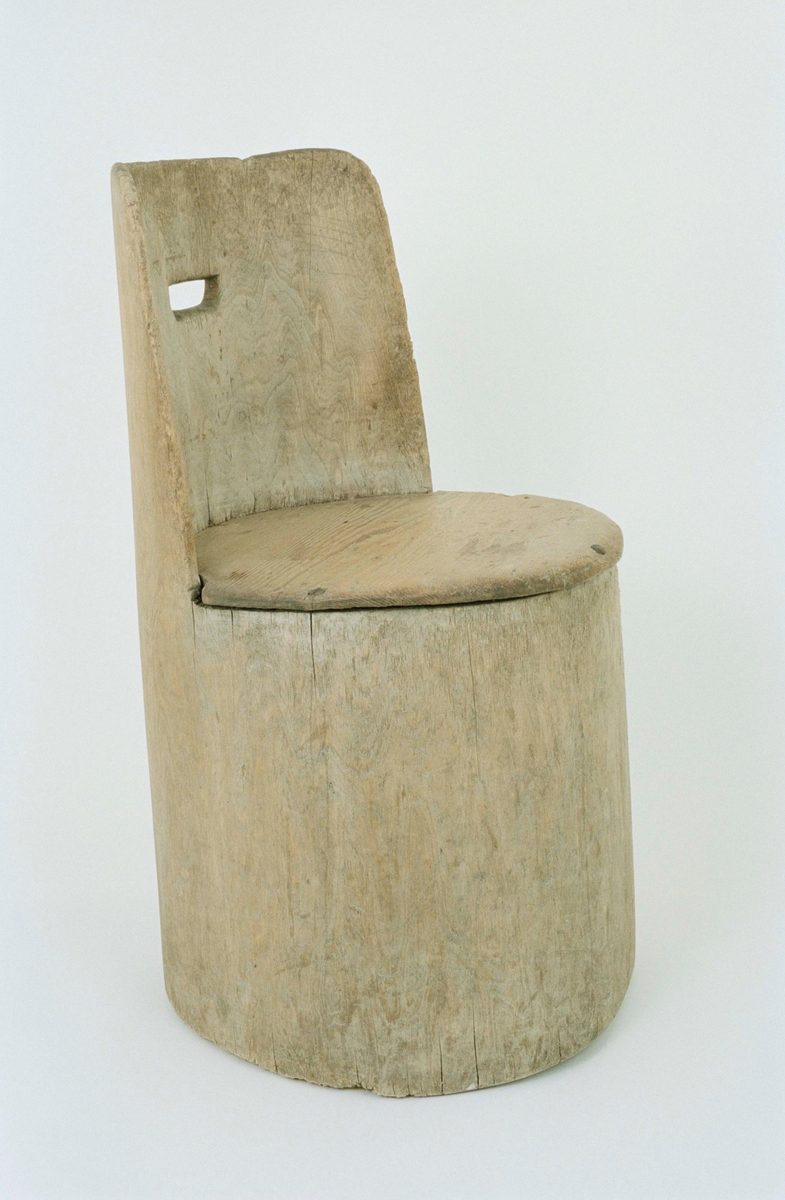 Kubbstol av urholkad stock av lövträ, stomme och rygg i ett stycke. Fastspikad sits av furu. Urtag för handtag i ryggen, spår av gulmålad bladdekor på ryggens baksida.