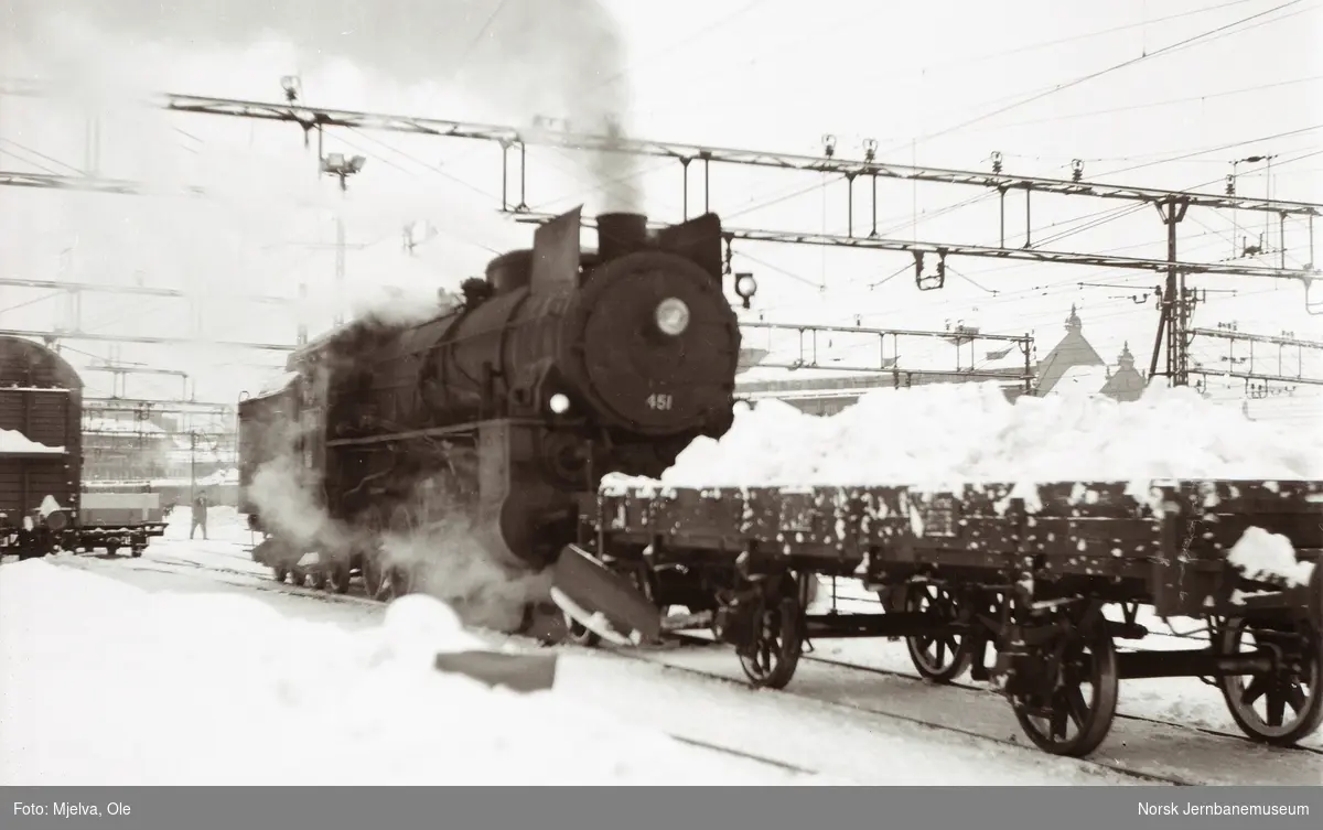 Damplokomotiv type 31b nr. 451 med godsvogn litra N2 lastet med snø på Oslo Østbanestasjon.