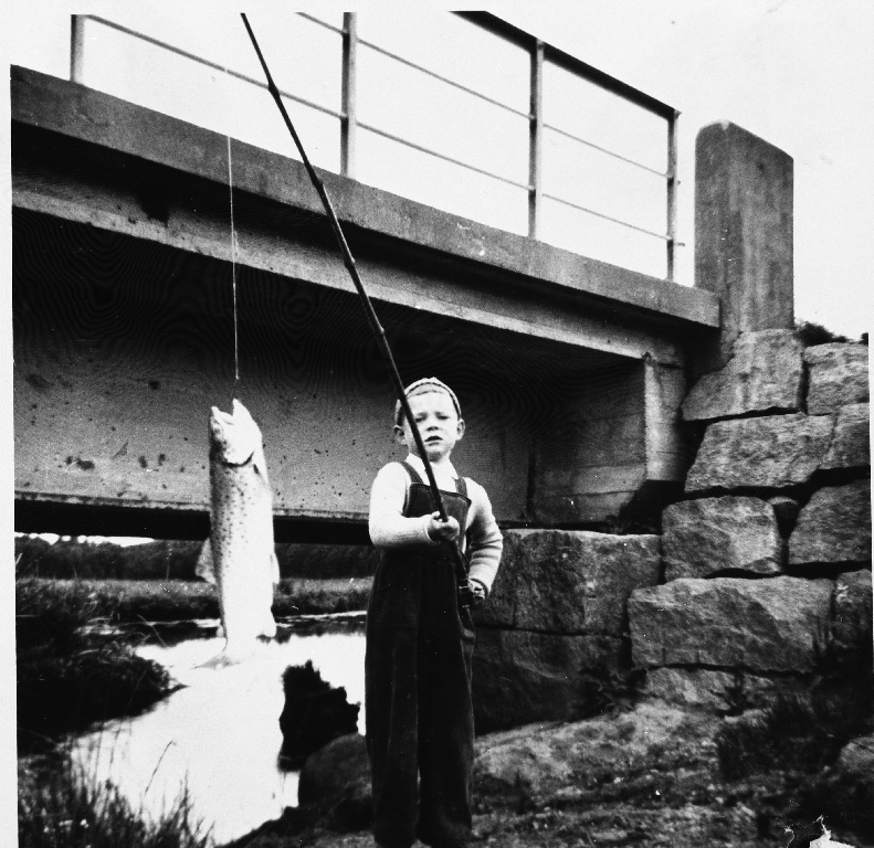 Sandor Horvat jr. (02.08.1974 - ) har fått aure på fiskestanga i "Ånå" ved brua. Idrettsbanen ligg like ved. Bak ser me mot Frøylandsvatnet.