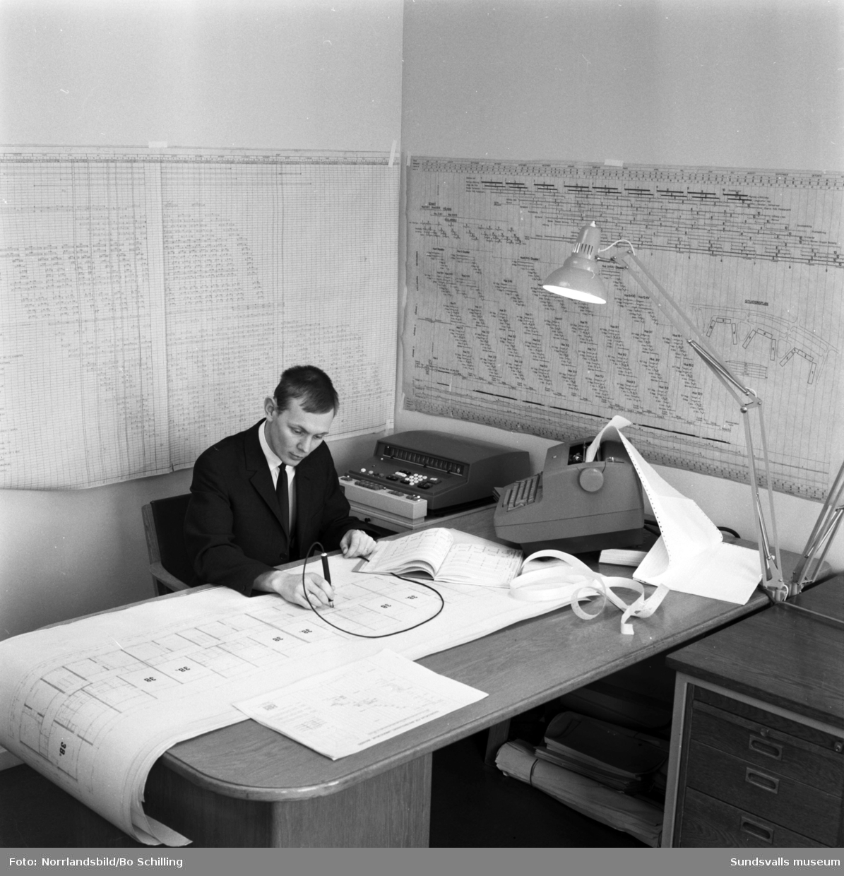 En man på Hallström & Nisses kontor hanterar planering och ritningar med hjälp av en datamaskin.