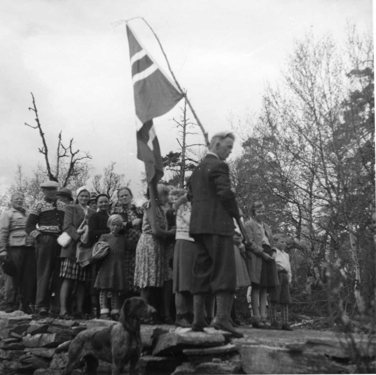 Mann med norsk flagg med flere personer i bakgrunnen