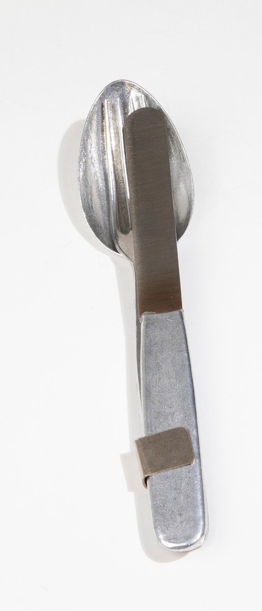 Matsked av lättmetall med fastskruvad liten hållare för att hålla samman skeden med kniven (JM 54960:2) och gaffeln (JM 54960:3). Förpackning: JM 54960:4.