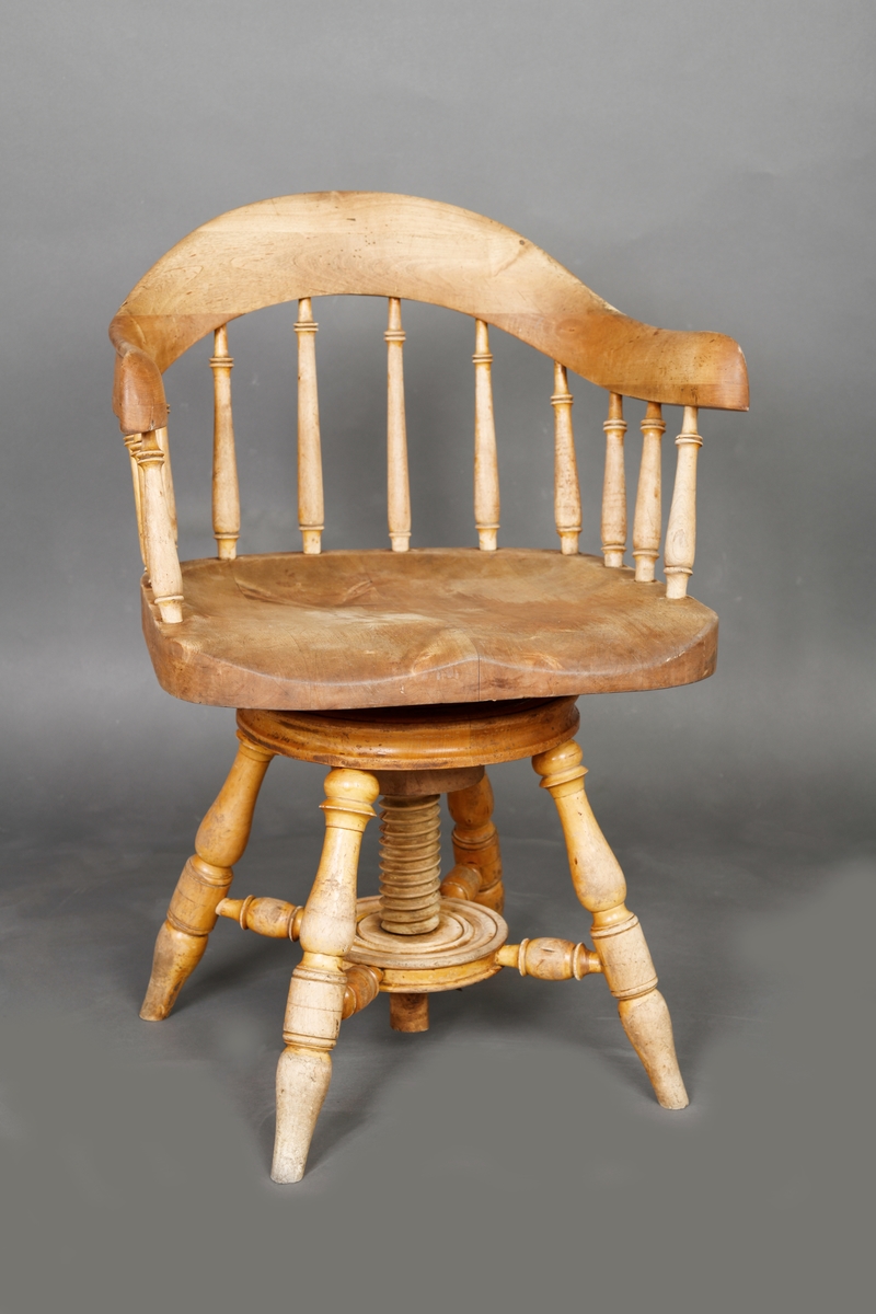 En stol med dreibart sete og armlener. Stolen er laget av heltre og har treforbindelser. Setet er bredt og dypt. Ryggen består av av 12 spiler/pinner som har enkel dreid dekor. Disse er festet i setet og i en bue som er øverst. Stolen har fire bein som står skrått ut fra midten på stolen. Midt under er det en konstruksjon som gjør at stolen er dreibar og kan justeres i høyden.