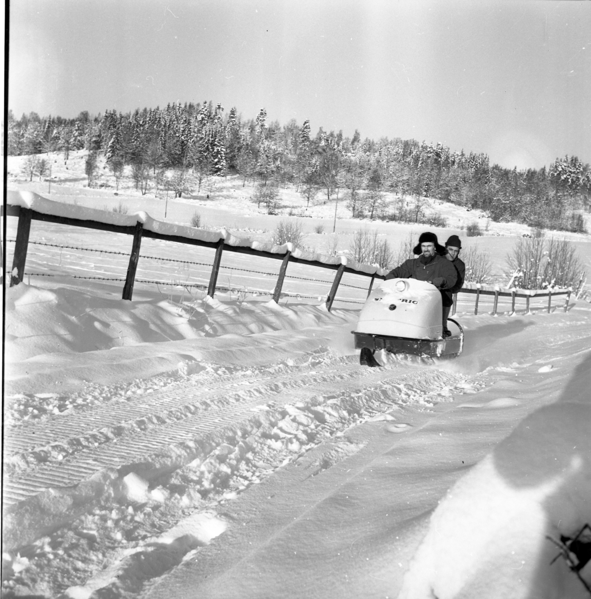 Paul Nes och Rolf Möller åker på snöskoter i ett mycket snörikt landskap.