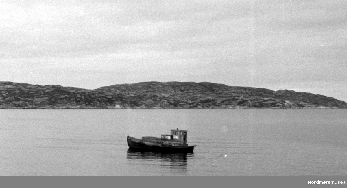 Foto av et lite fartøy, like ved Storvik Mekaniske verksted i Kristiansund. Fotograf er Nils Williams. Fra Nordmøre museums fotosamlinger.