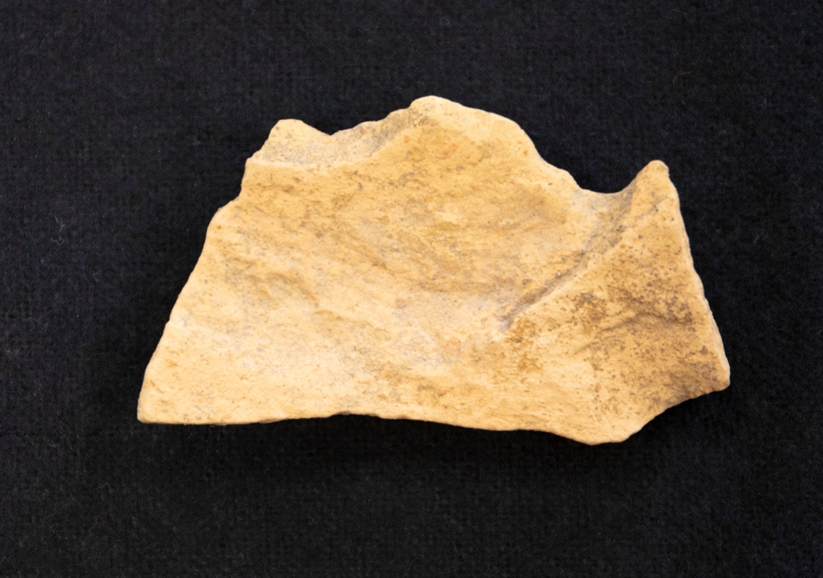 Fragment av botten av lergods. Ljust gods, oglaserad.

Funnen i anläggning S23.
Grävningsledaren ändrade sedan anläggningsbeteckningen i grävrapporten till K23.
Fynden kommer från en arkeologisk utgrävning/schaktövervakning av Brätte 1:8 ledd av Oscar Ortman 2018.