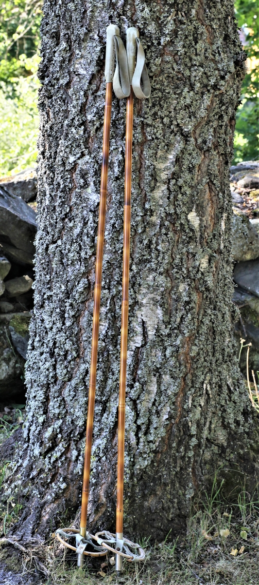 Et par skistaver av bambus med håndtak, trinser og pigger.