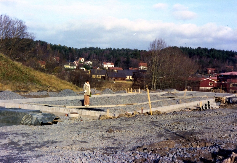 Gun-Britt Eklund står på grunden till Högenvägen 162 cirka 1977. Bostäder utefter Streteredsvägen ses i bakgrunden.