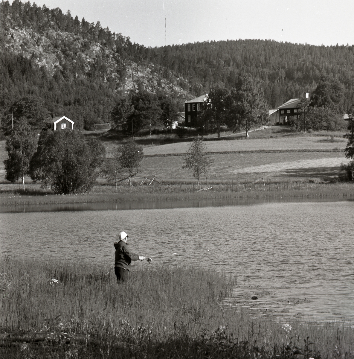 En person fiskar med kastspö vid Kläpptjärnen, Skog 1974.