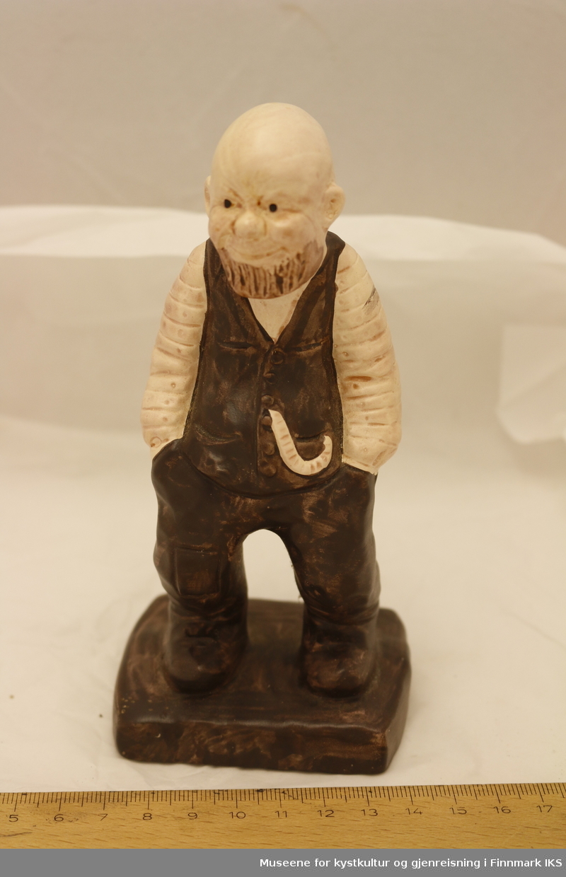 En malt porselensfigurin av en mann med skjegg, ikledd 1800-talls klær med vest og skjorte og lommeur. 