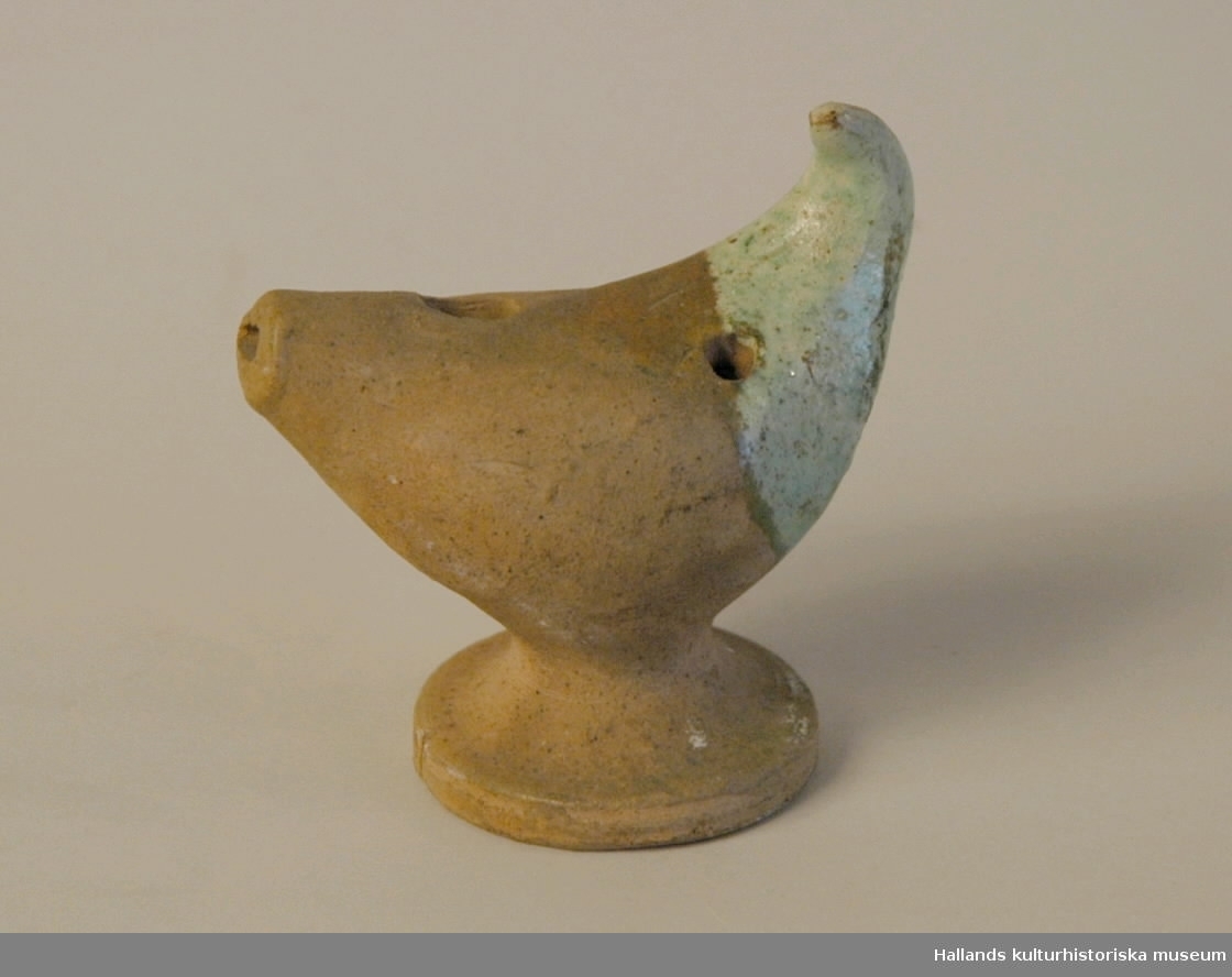 Lergök av keramik, grön glasyr en bit på motsatt sida av munstycket.Höjd= 9 cm.Bredd? (Diameter fot)= 5 cm. Bredd?:50 mm. 