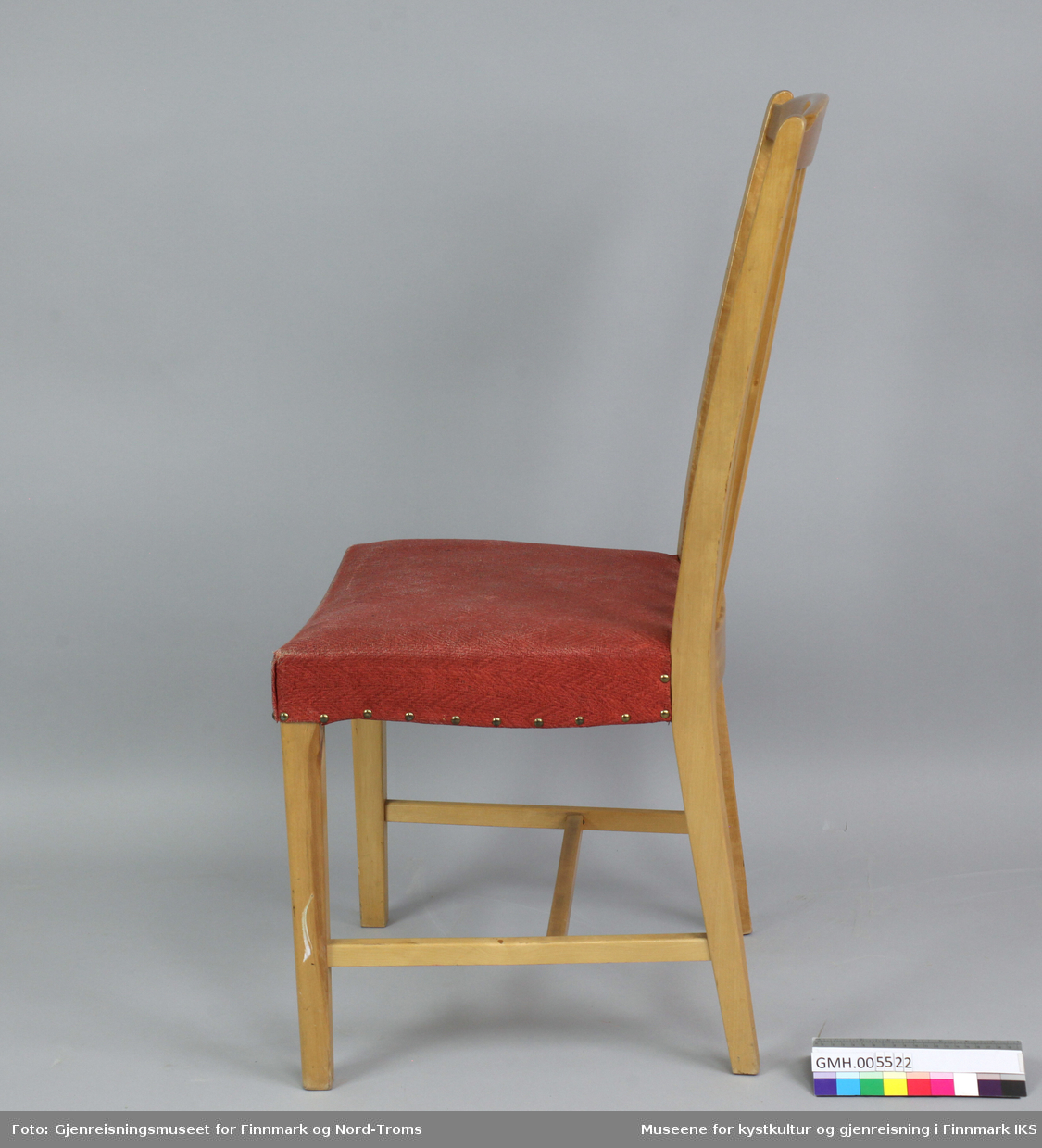 Stolen er bygget i tre med åtte profilerte, flate spiler i ryggen som er plassert to og to. Ryggen er svakt buet og har et buet tverrstykke oppe. Sidestolpene på ryggen danner også bakbenene til stolen. De buer innover fra topp til setet og utover fra setet til gulvflaten. Benene er firkantede og frambenene er rette. Stolen har sidesprosser og en tverrsprosse i midten, mellom sidesprossene.Setet består av en tynn polstret kryssfinérplate og har et rødt, vevd trekk med fiskebensmønster. Trekket er festet med nagler på sidene og bak mot ryggen.