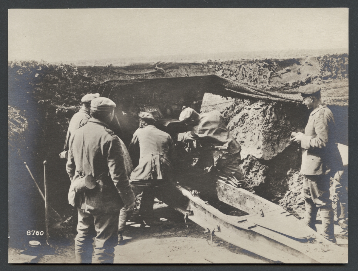 Bilden visar en grupp soldater som arbetar kring en artilleripjäs med stor kaliber. 

Originaltext: "Tysk 15-cm.-haubits under eldgivning vid Albert