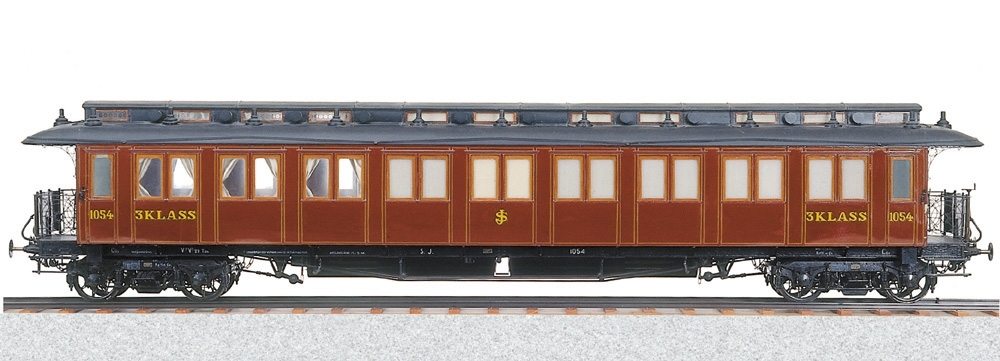 Modell av SJ 3:e klassvagn av rödbrun plåt, försedd med lanternin och grindar. Boggier. Grå gardiner i fönstren. Träinredning.

Skala 1:10,  Litt Co1 Nr 1054