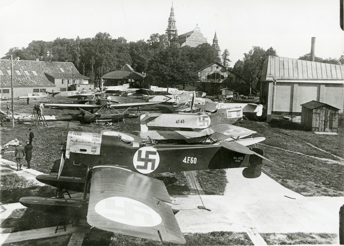 Finska flygbåtar på besök vid Flygverkstäderna på Galärvarvet 1925. I bakgrunden till vänster syns galärskjul 17, där flygingenjörerna hade kontor. I mitten syns flygverkstäderna och till höger hangarer. I bakgrunden Nordiska museet