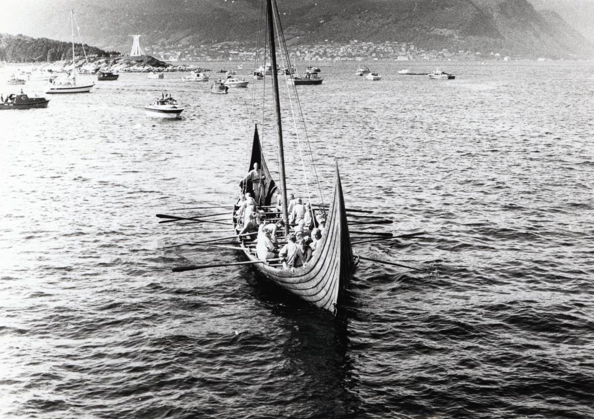 En stor gruppe mennesker som ror et vikingskip, replikaen "Kvalsundskipet". Fra 1000- års feiringen i Hjørungavåg.