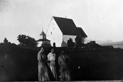 Portrett av tre kvinner stående med Trondenes kirke i bakgru
