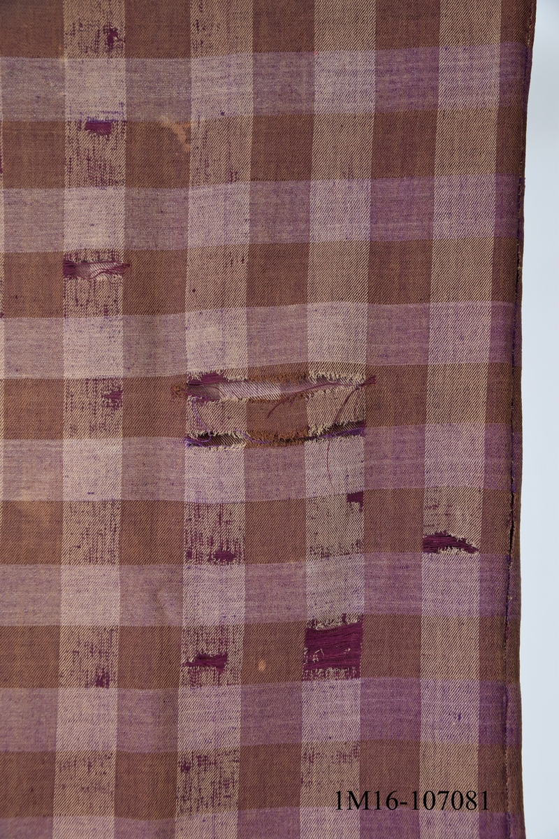 Schal i halvylle, brun, beige, och lila. Har tillhört Karl Edberg, Mjädrunga, Floby och använts som förlaga till schalen i Vilskedräkten.