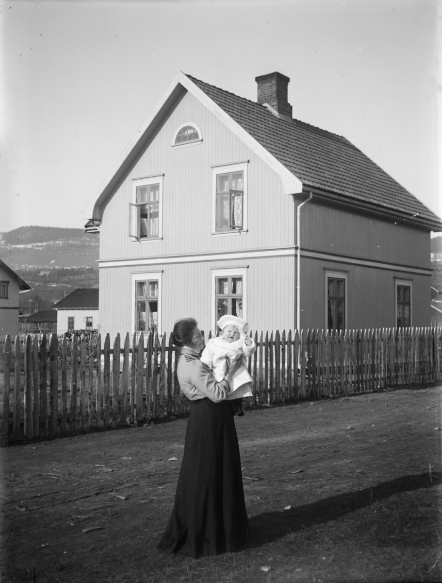 Kvinne med barn i gata fremfor et bolighus