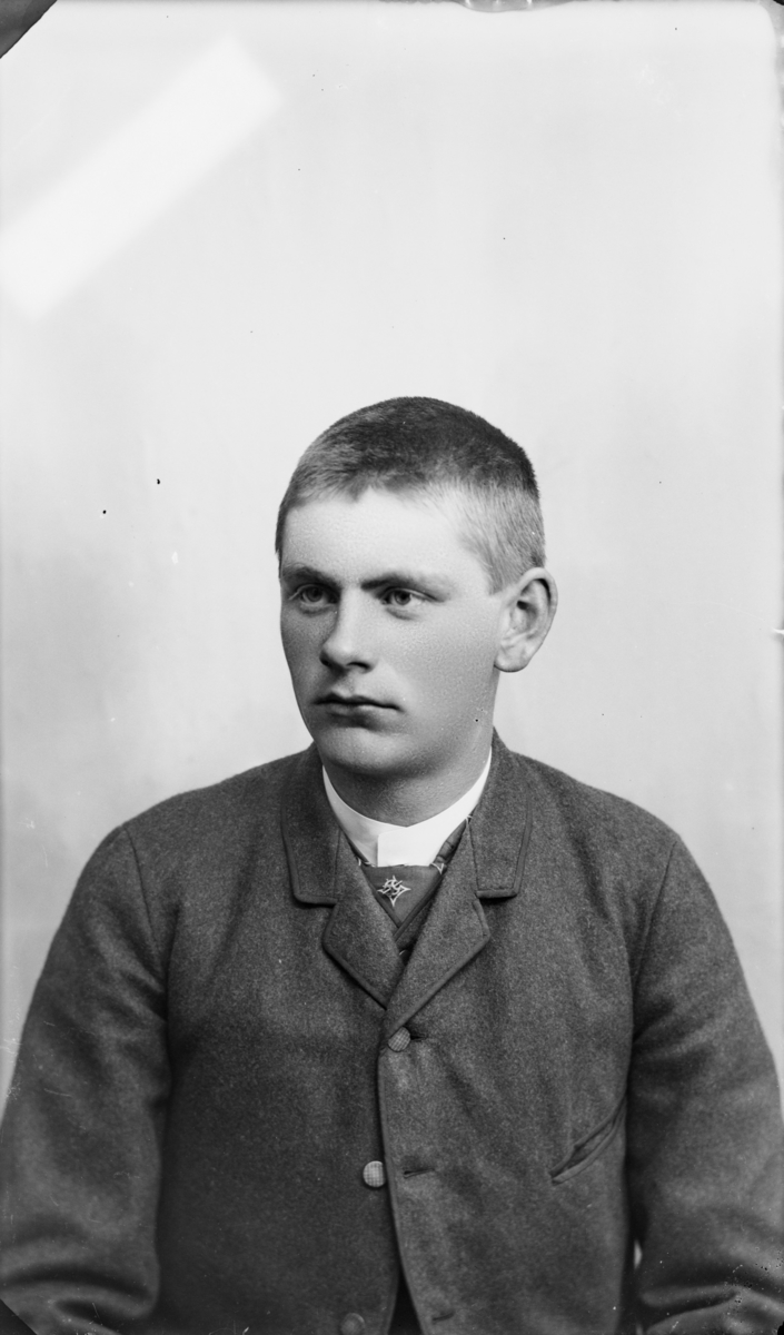 Portrett av ung mann med kort hår og vadmelsjakke. Etter MPLs regnskapsbok er dette Ola Ellingsbø, Hedalen, Vaage.