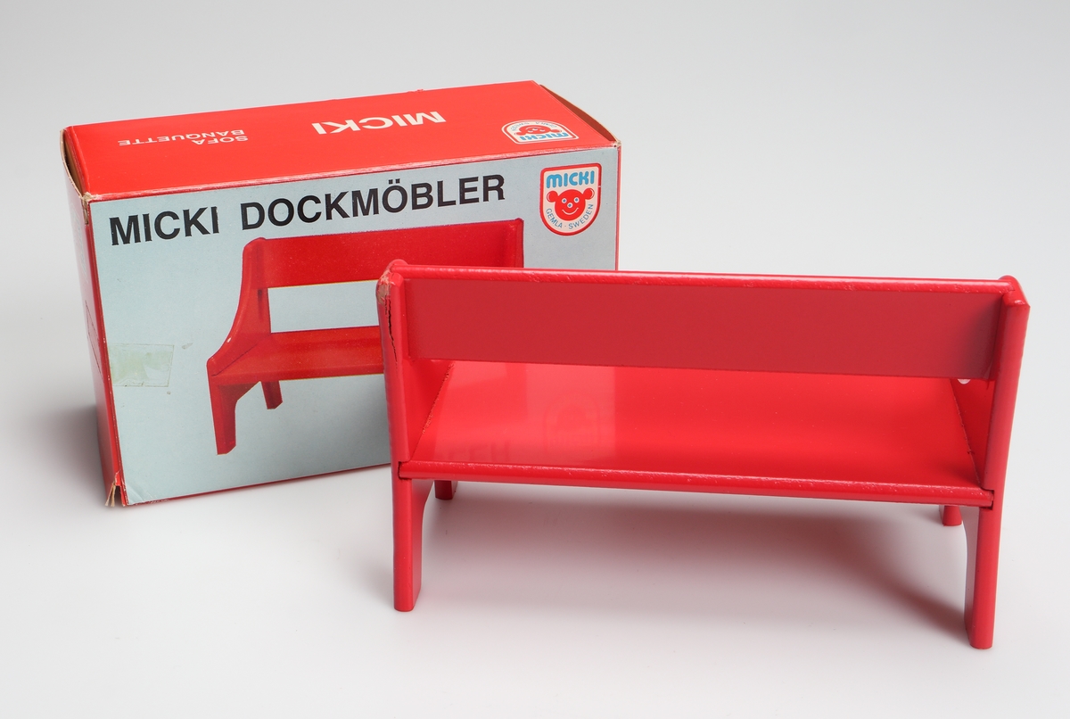 Rödlackerad soffa (dockmöbel) tillverkad av träfiberskiva. Soffan är förpackat i en röd och vit pappkartong med text på svenska, tyska, engelska och franska.

Inskrivet i huvudkatalog 1982.