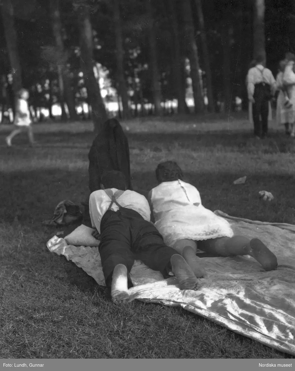 Motiv: Utlandet, Bad v. Berlin 147 - 156 ;
Vy över en badstrand med människor som sitter på marken och människor som badar , en man och en kvinna ligger på en filt i en park, anteckning på kontaktkarta 149 "Badande barn".